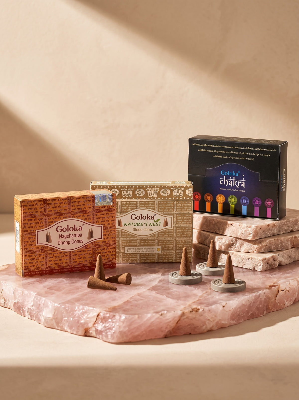 Goloka Dhoop Cones packs with loose cones on a rose quartz slab